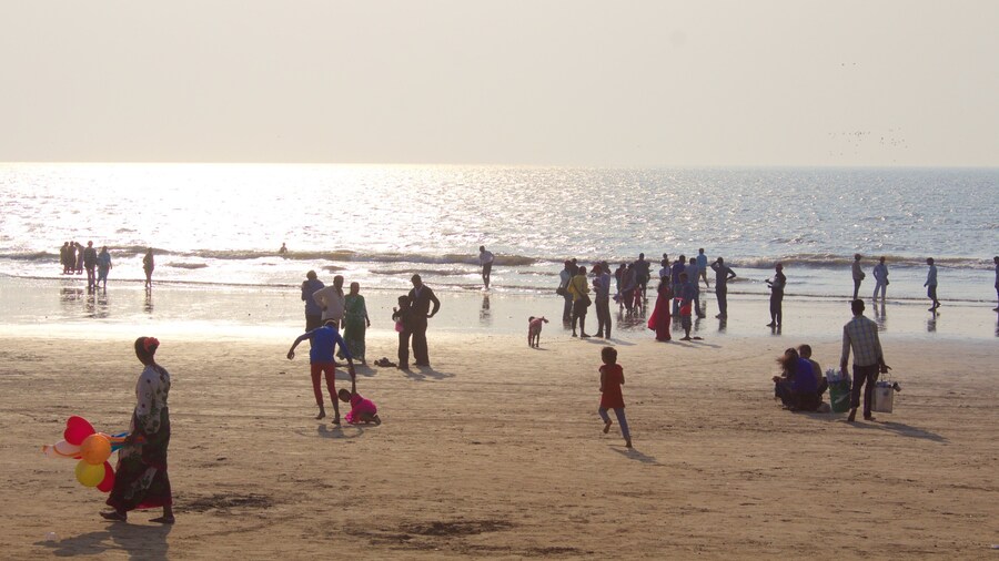 Juhu Beach which includes a sandy beach and a sunset as well as a large group of people