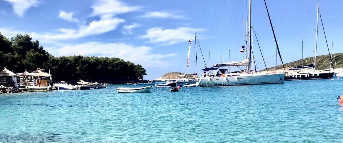 Clear turquoise water with visible rocks and boats.
