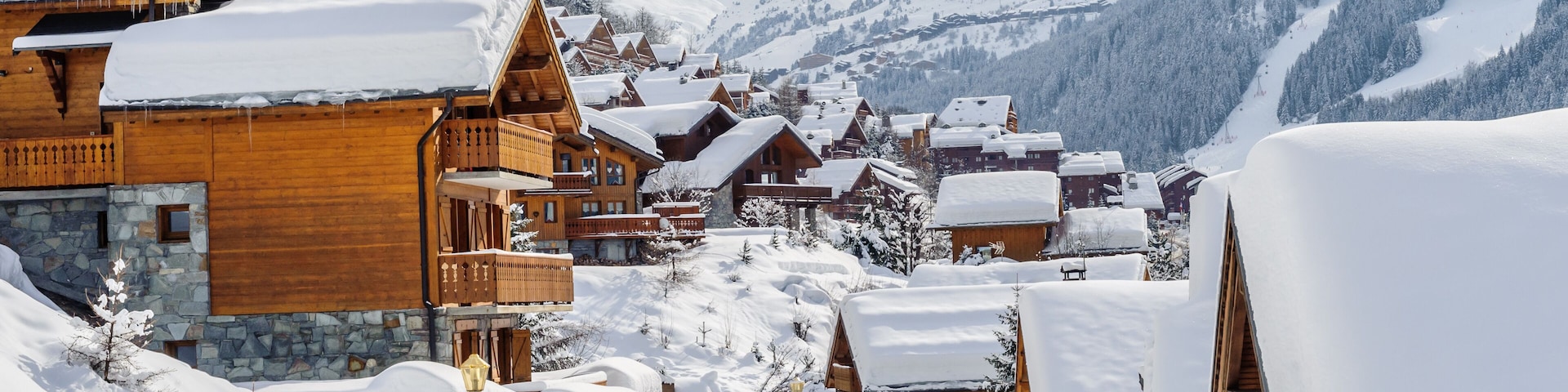 Un pueblo cubierto de nieve con casas de madera y montañas al fondo.