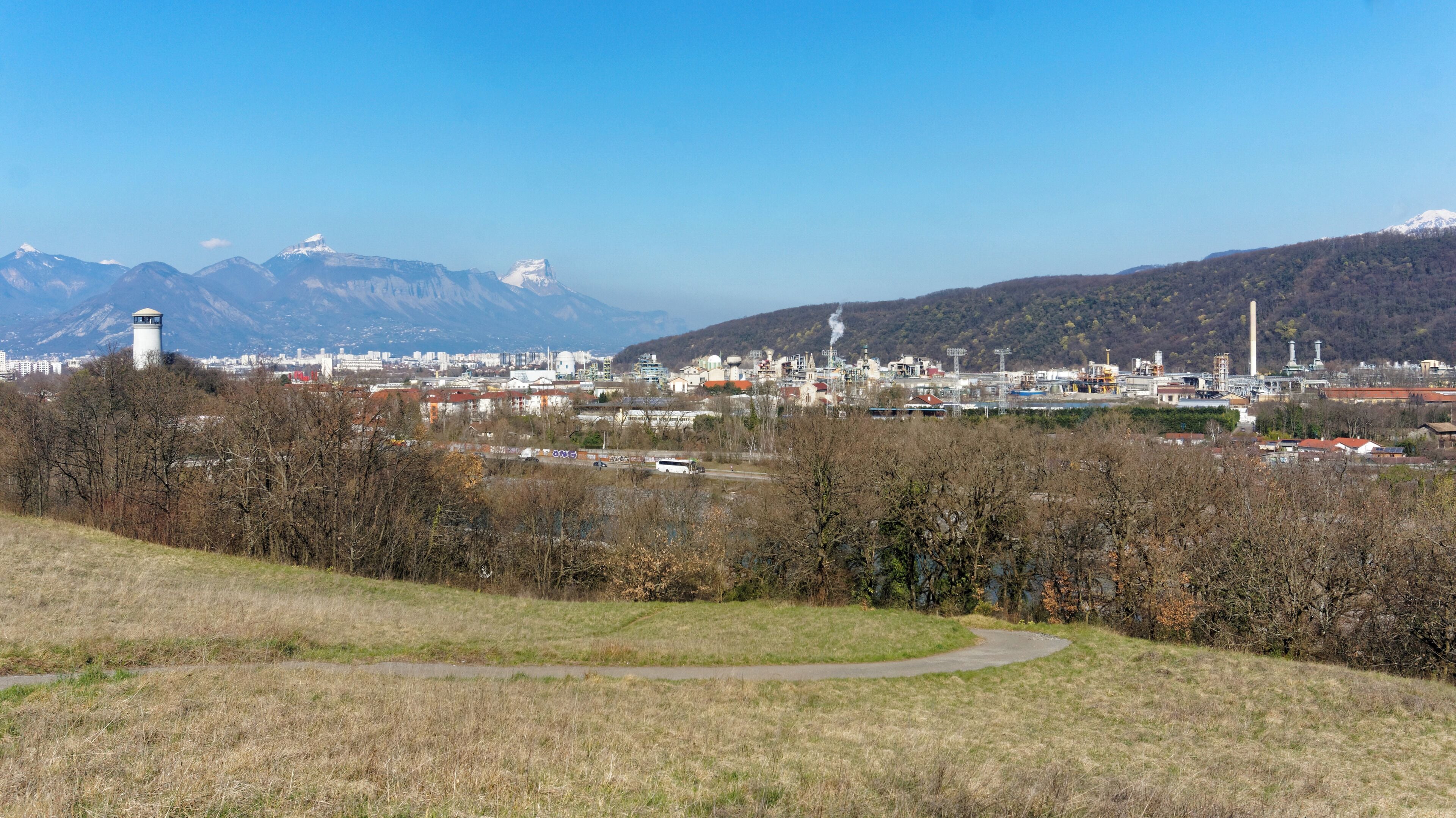 A cityscape with mountains in the background, a water tower, and industrial buildings.