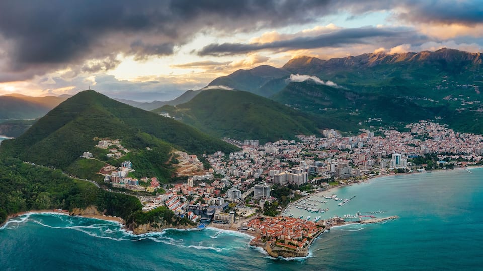 A coastal city with a mountainous backdrop, a harbor, and a densely built urban area.