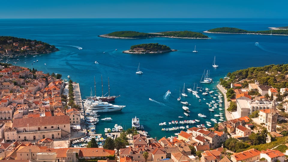 A coastal town with a marina filled with boats, surrounded by water and islands.