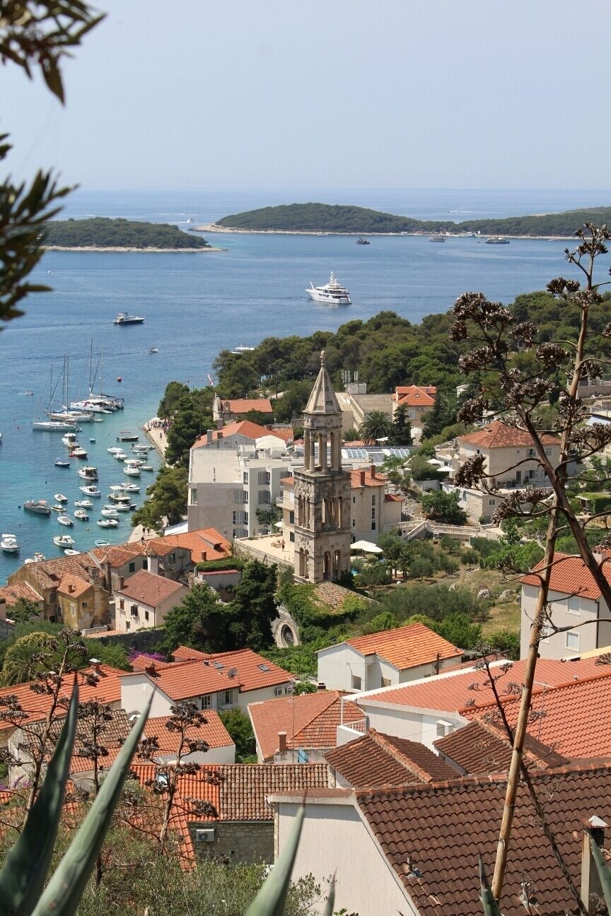 A coastal town with a prominent church, boats in the harbor, and red-roofed buildings.