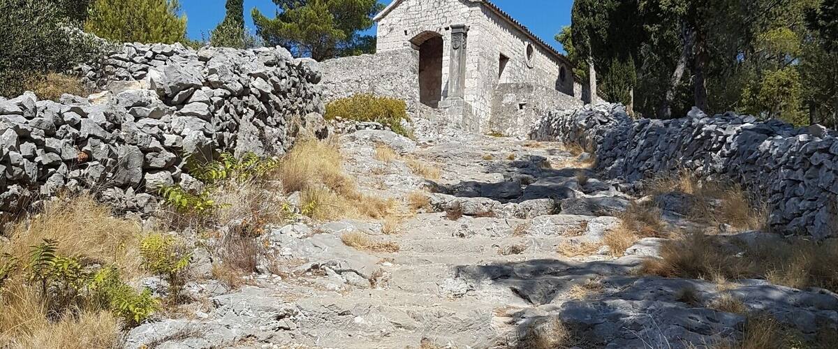 A stone church with a bell tower on a rocky hillside.