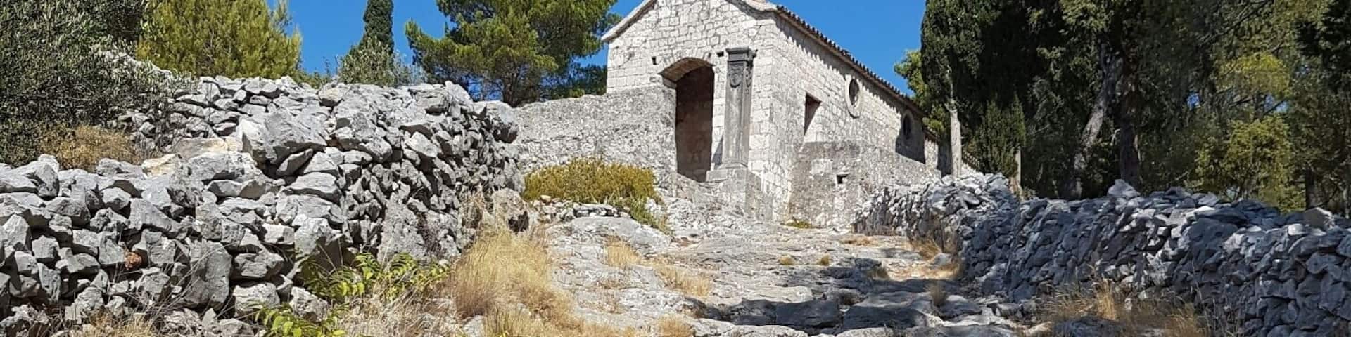 A stone church with a bell tower on a rocky hillside.