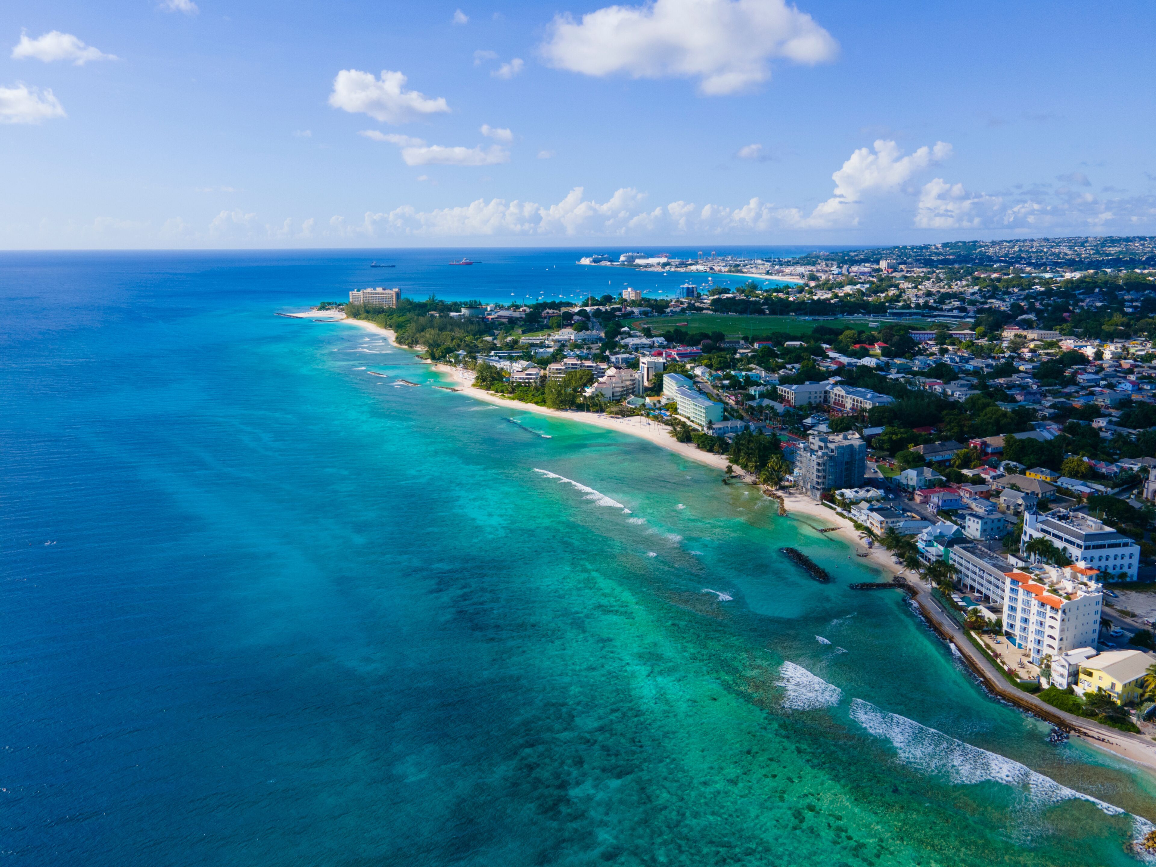 A coastal city with a clear blue sea, a sandy beach, and dense urban development.