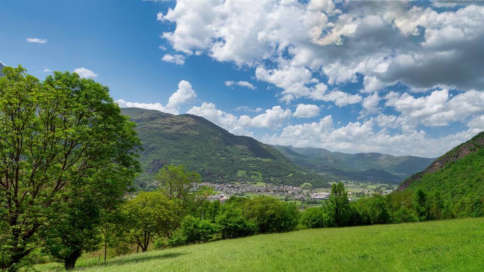 A valley with a town, green hills, and a mountain in the background.