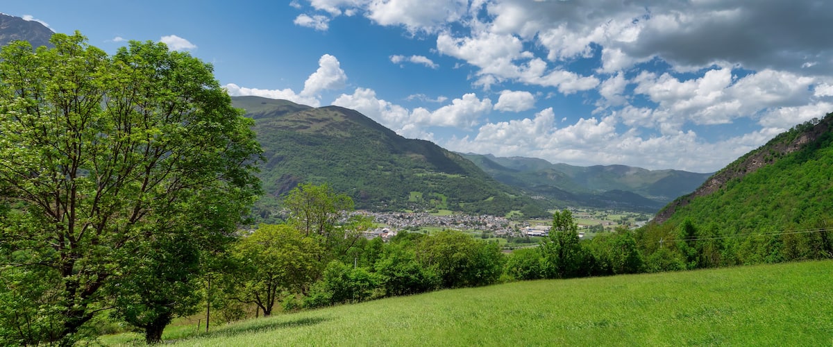 A valley with a town, green hills, and a mountain in the background.