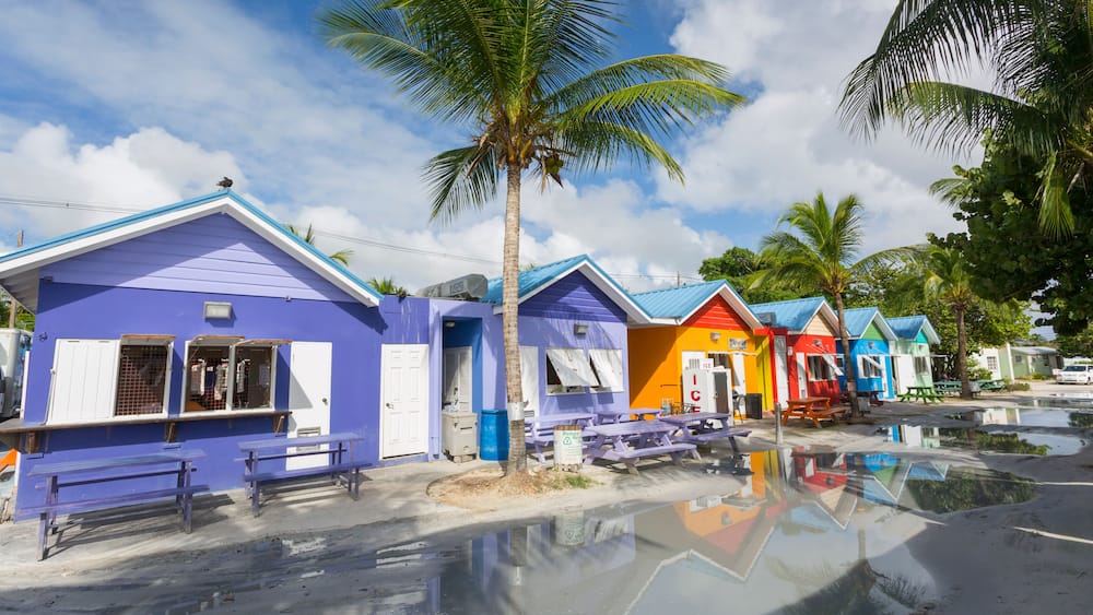 Colorful beachside buildings with palm trees and a reflective water surface.
