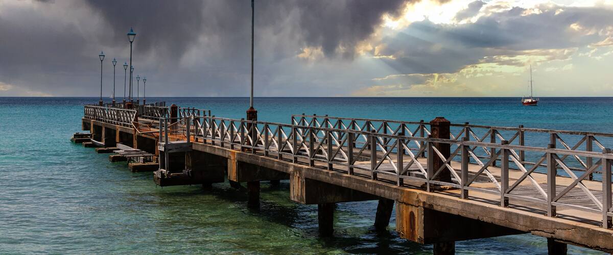 A pier extending into the ocean with a sailboat in the distance.