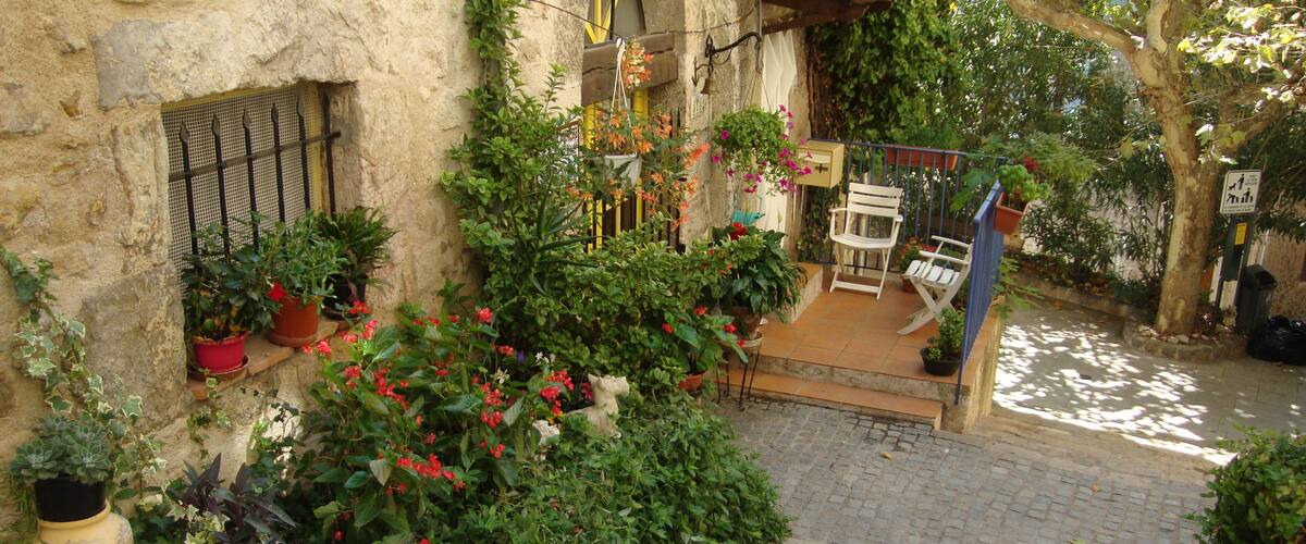 A stone staircase leading to a terrace with potted plants, a white bench, and a hanging flower pot.
