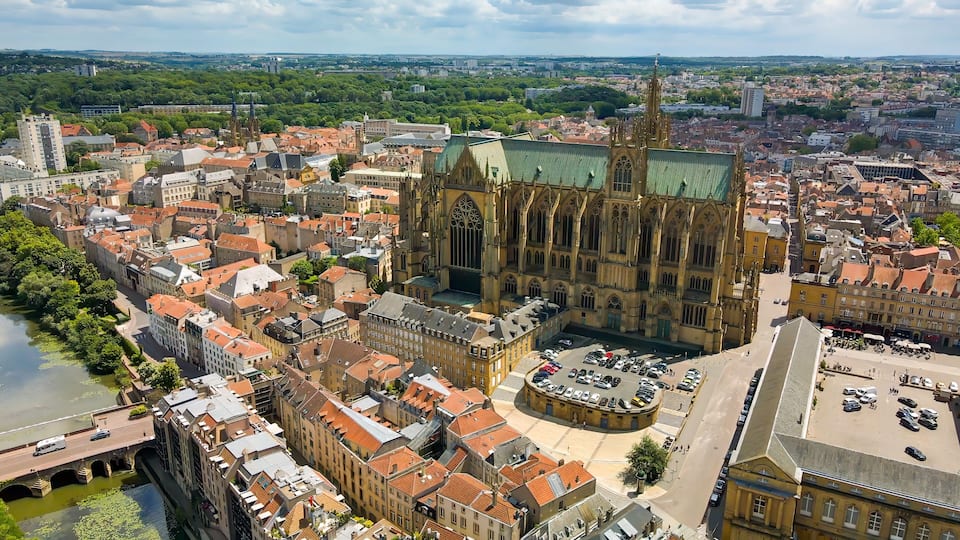 A cathedral with a green roof surrounded by historic buildings and a river.
