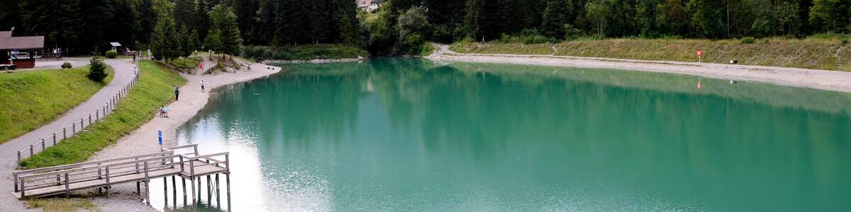 Un lac entouré de montagnes, une jetée en bois et un sentier.