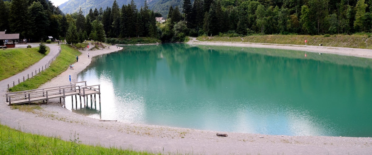 Un lac entouré de montagnes, une jetée en bois et un sentier.