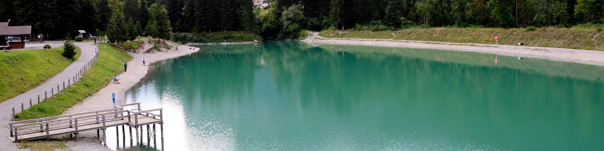 A lake surrounded by mountains, a wooden dock, and a pathway.