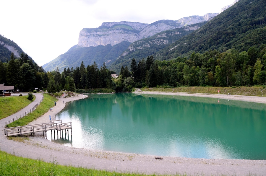 Un lac entouré de montagnes, une jetée en bois et un sentier.