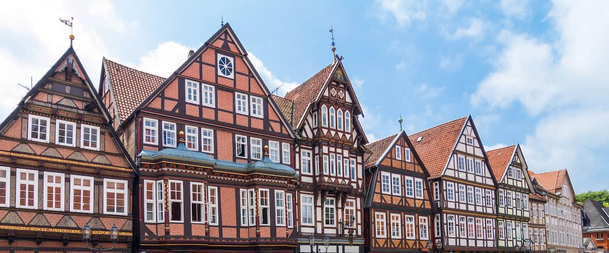 A row of traditional half-timbered houses with steeply pitched roofs and a tower with a spire.
