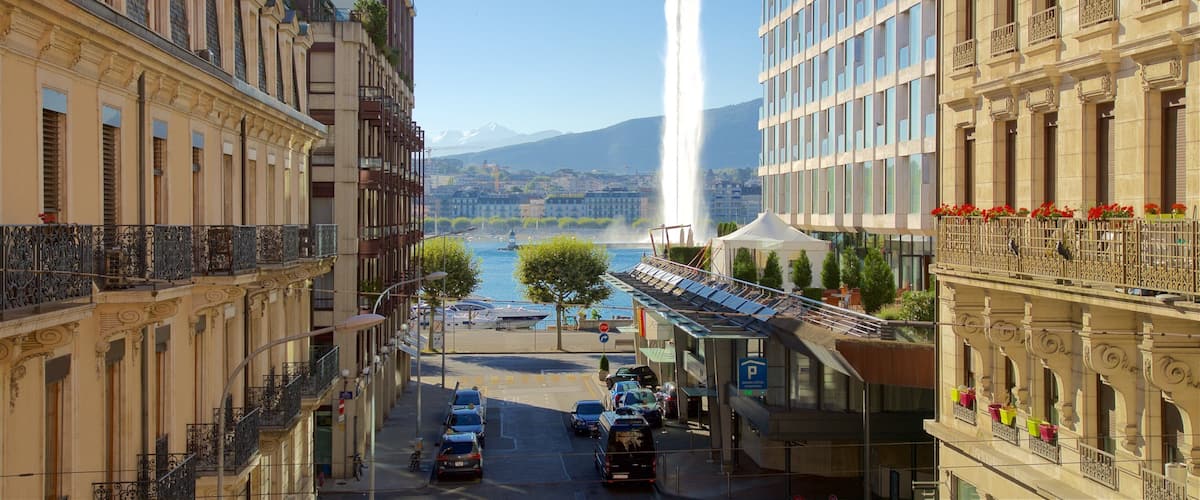 A city street with historic buildings, a fountain, and a mountain in the background.