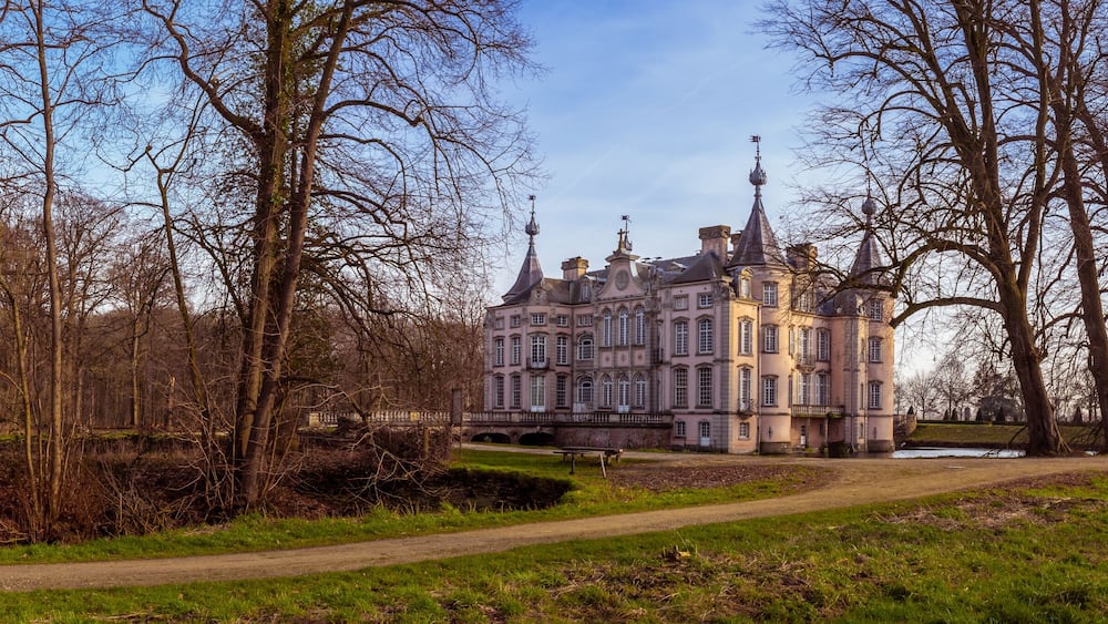 A historic building with multiple towers, surrounded by a park with a pathway and leafless trees.