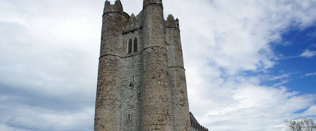 A tall stone tower with battlements, surrounded by a cemetery with gravestones.