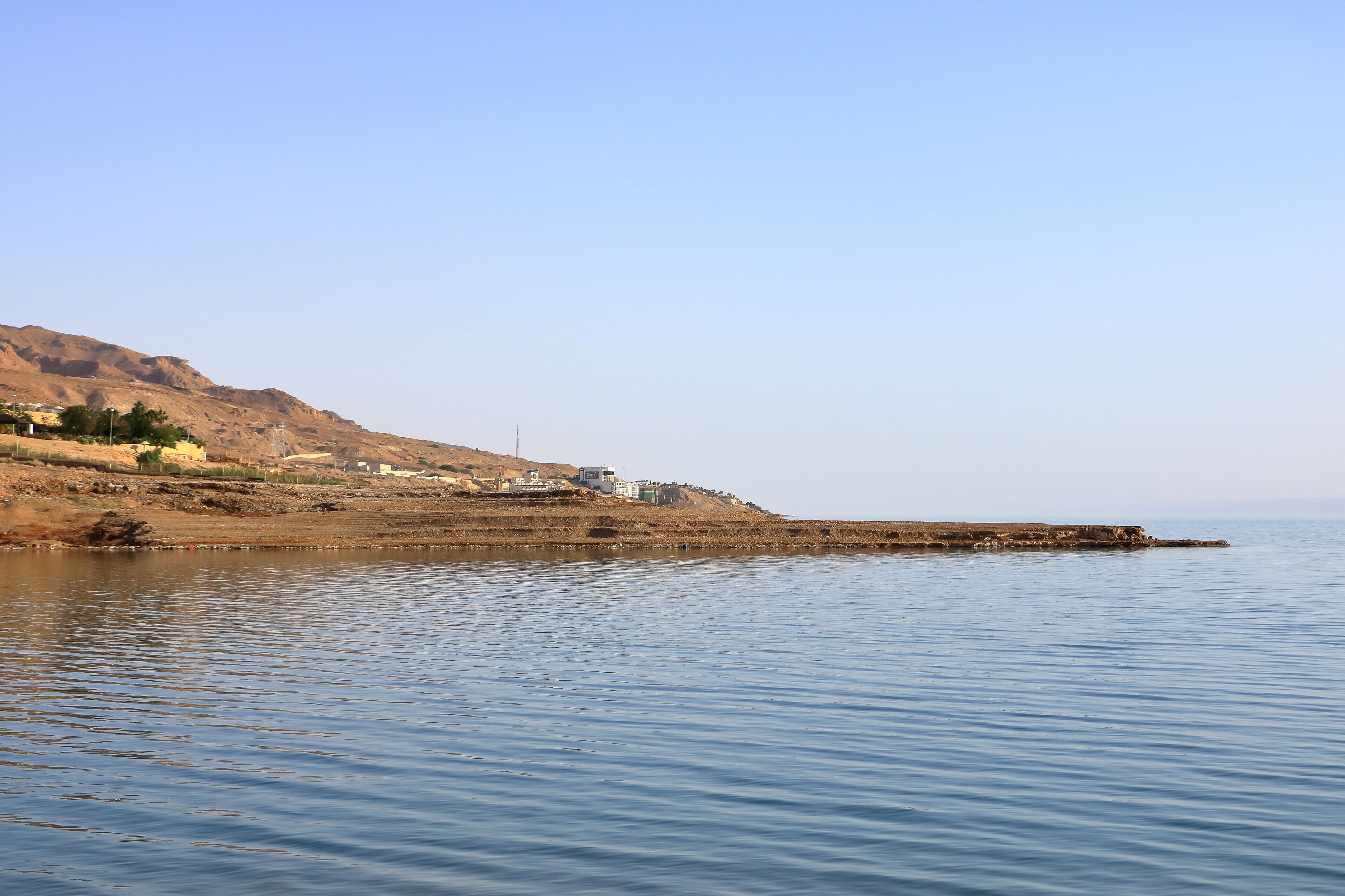 A calm body of water with a rocky shoreline and a distant mountain range.