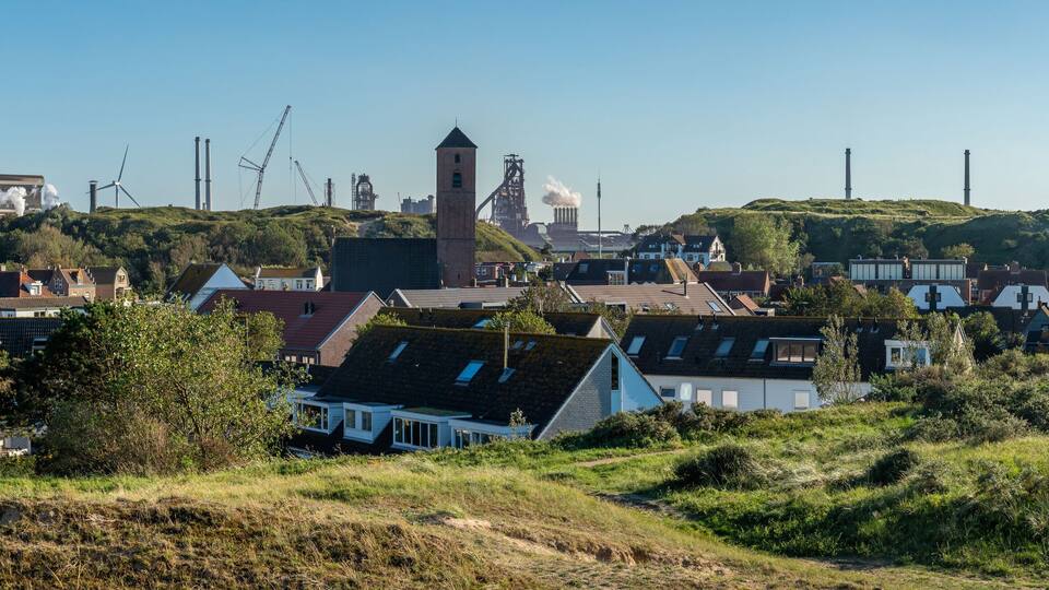 A coastal town with wind turbines, a church, and residential buildings.