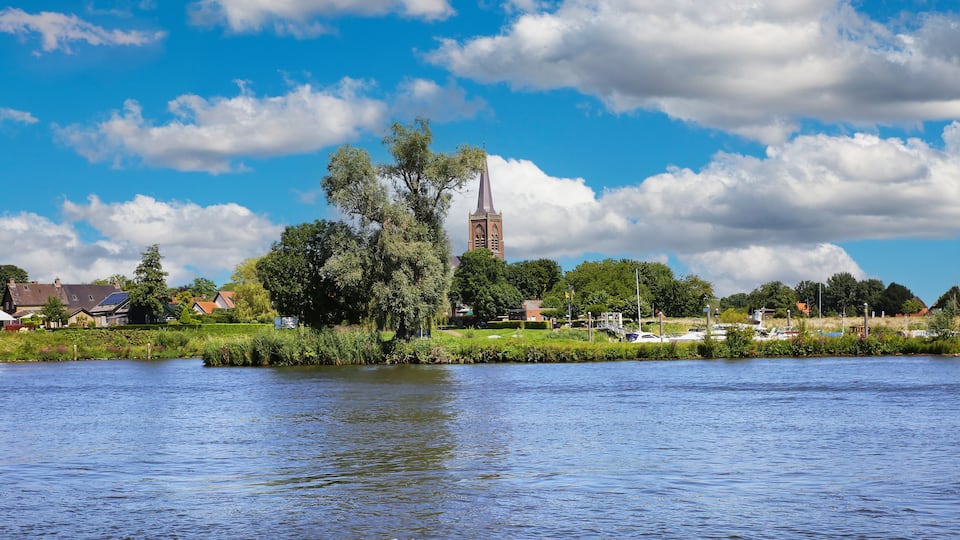 A river with a church steeple and houses along the banks.
