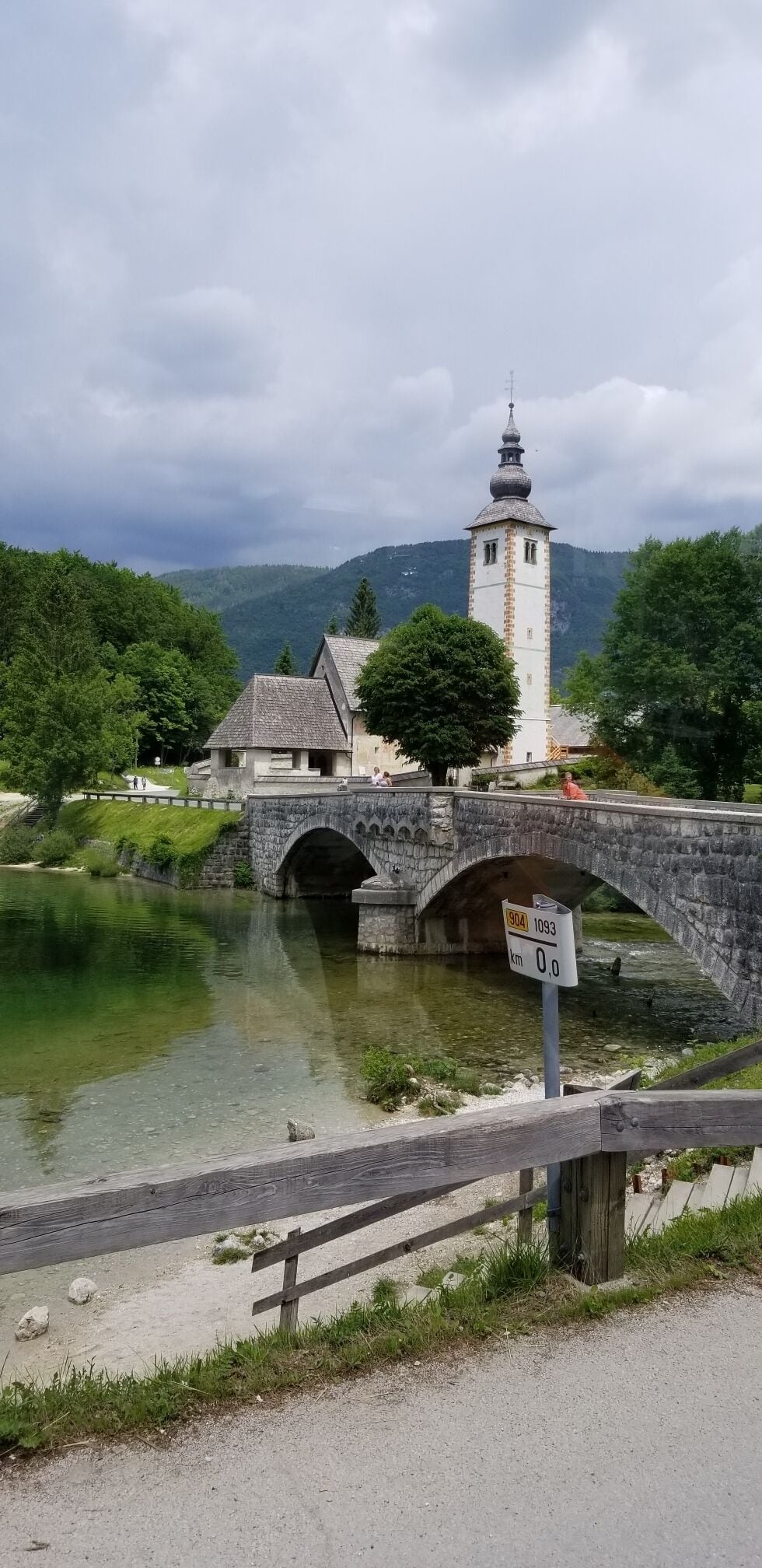 A stone bridge over a river, a tower, and a forested hillside.