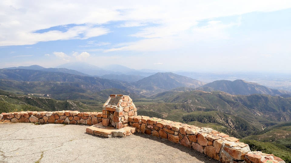 A stone wall with a stone bench overlooking a mountainous landscape.
