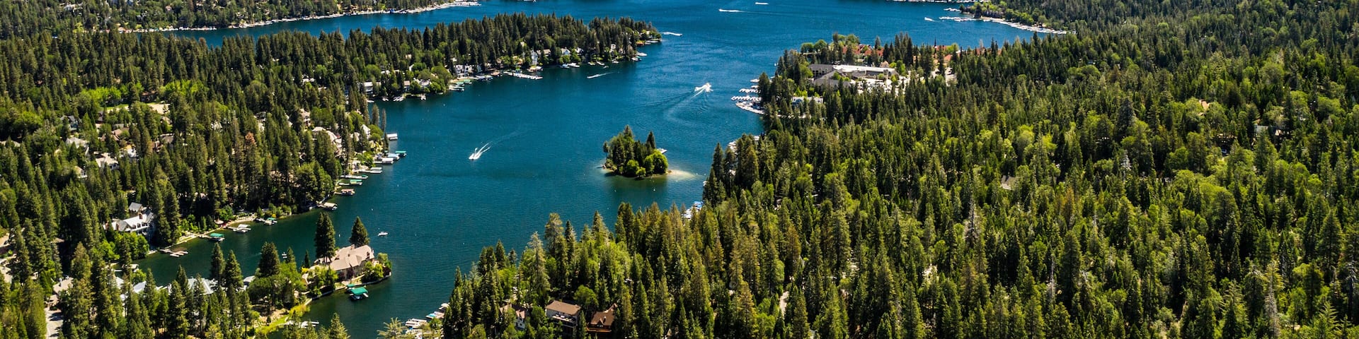 Aerial, quadcopter panorama of Lake Arrowhead in the San Bernardino Mountains, California on a sunny, clear day with blue sky, blue water, green pine trees and purple mountains