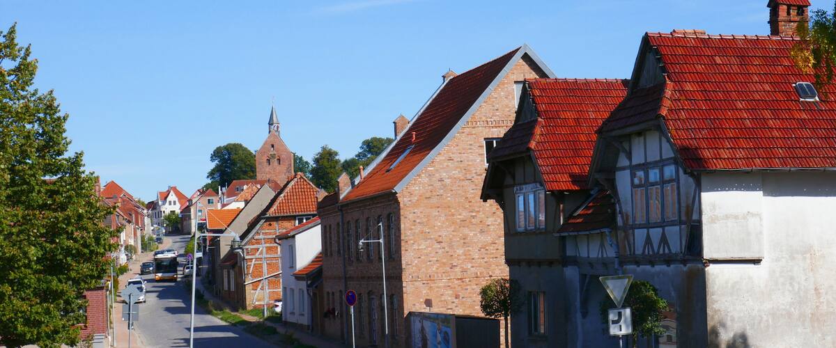 A street lined with historic buildings with red-tiled roofs and a clear blue sky.