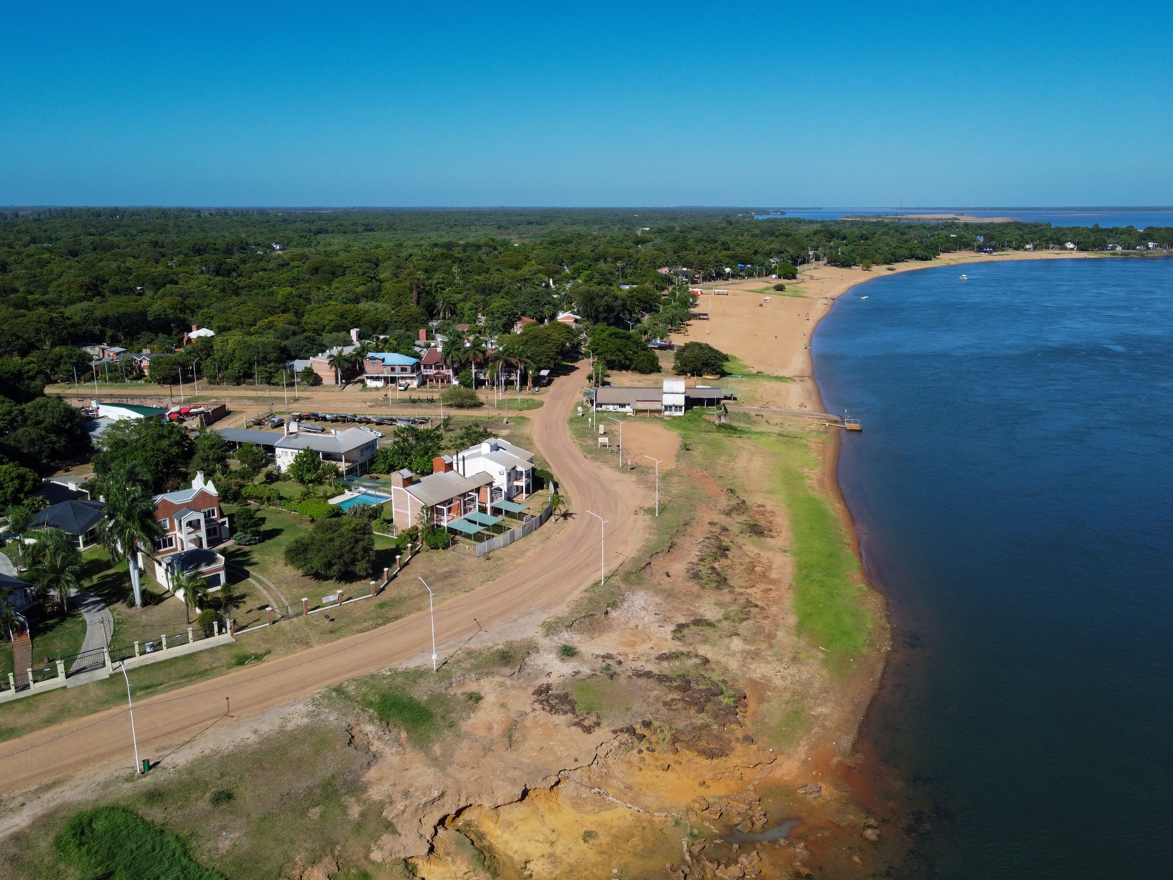 Discover the harmony of Paso de la Patria. The waterfront curve reveals sunny beaches, residences, and leisure spaces, a perfect day in Corrientes.
