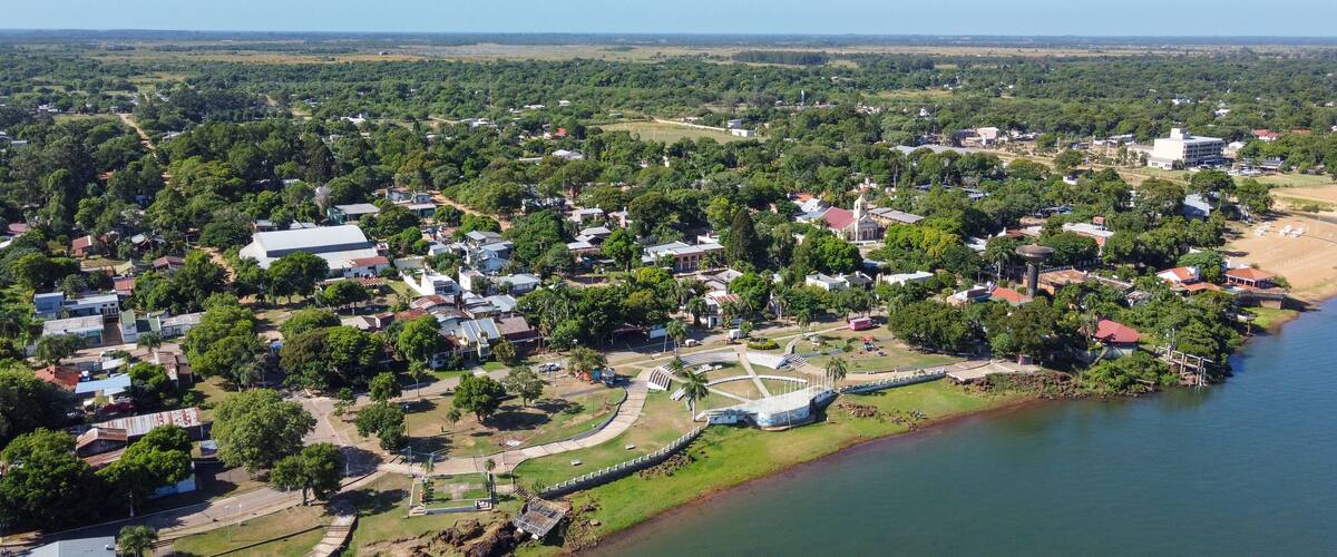 An aerial view of a coastal town with a river, green areas, and a mix of residential and commercial buildings.