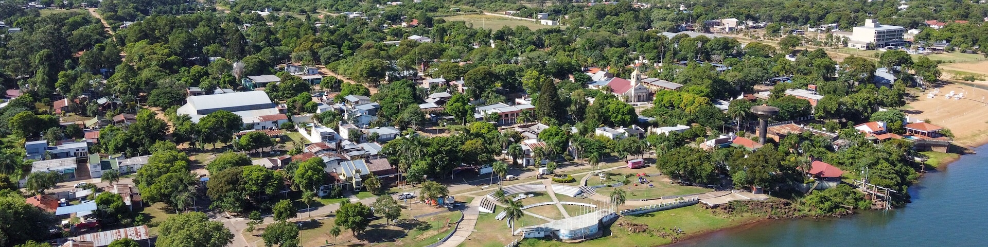 An aerial view of a coastal town with a river, green areas, and a mix of residential and commercial buildings.