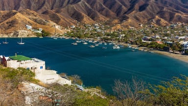 Uma vila costeira com montanhas ao fundo, barcos na água e casas ao longo da costa.