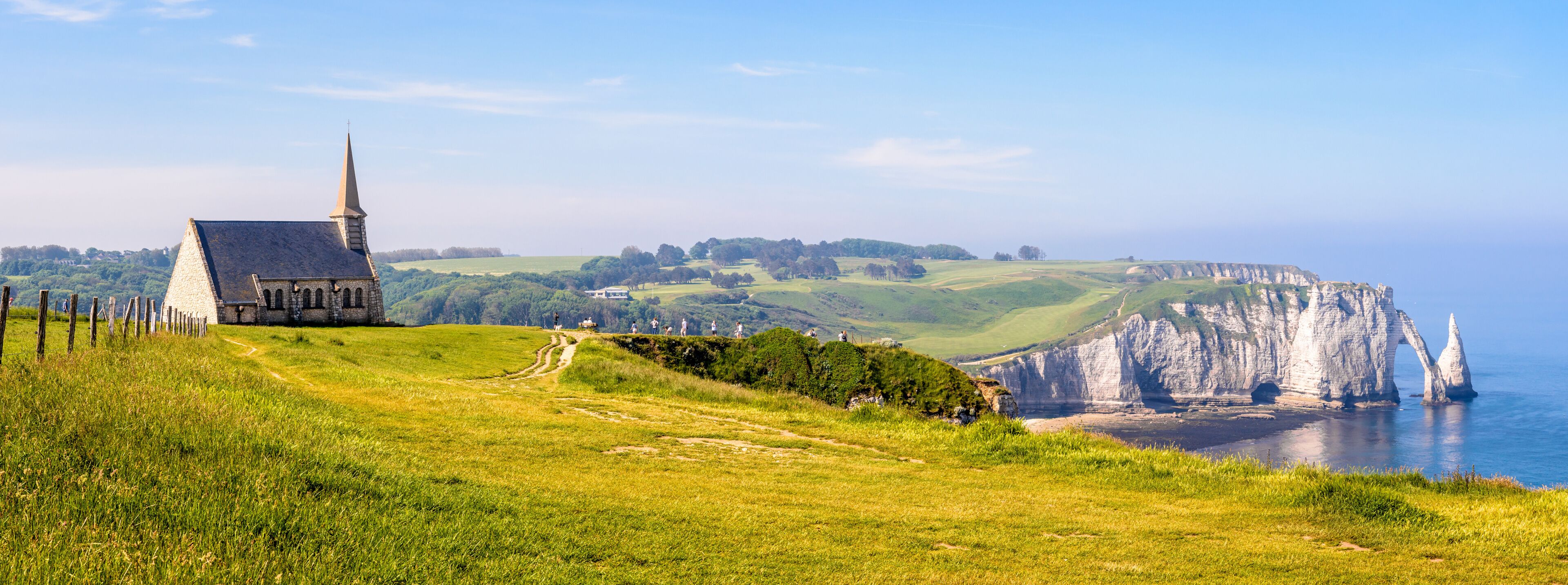 A church on a grassy hill, cliffs, and a coastal view.