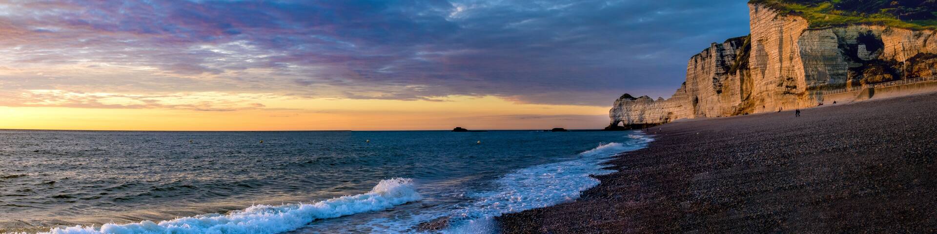 A coastal landscape with a cliff, beach, and a distant island.