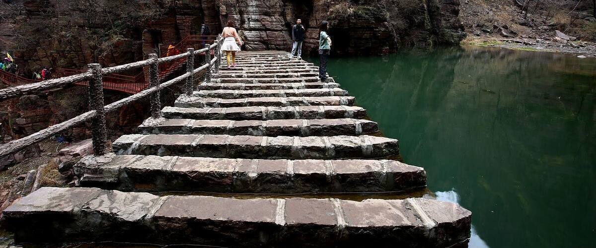 A stone staircase leading up a rocky gorge with a river at the bottom.