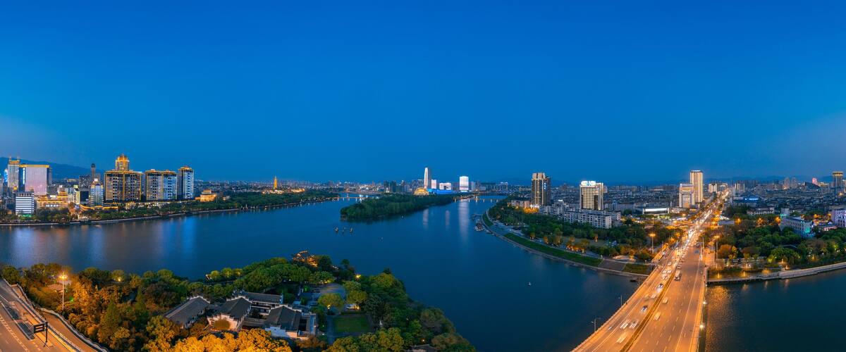 A cityscape with a river, modern buildings, and a bridge.