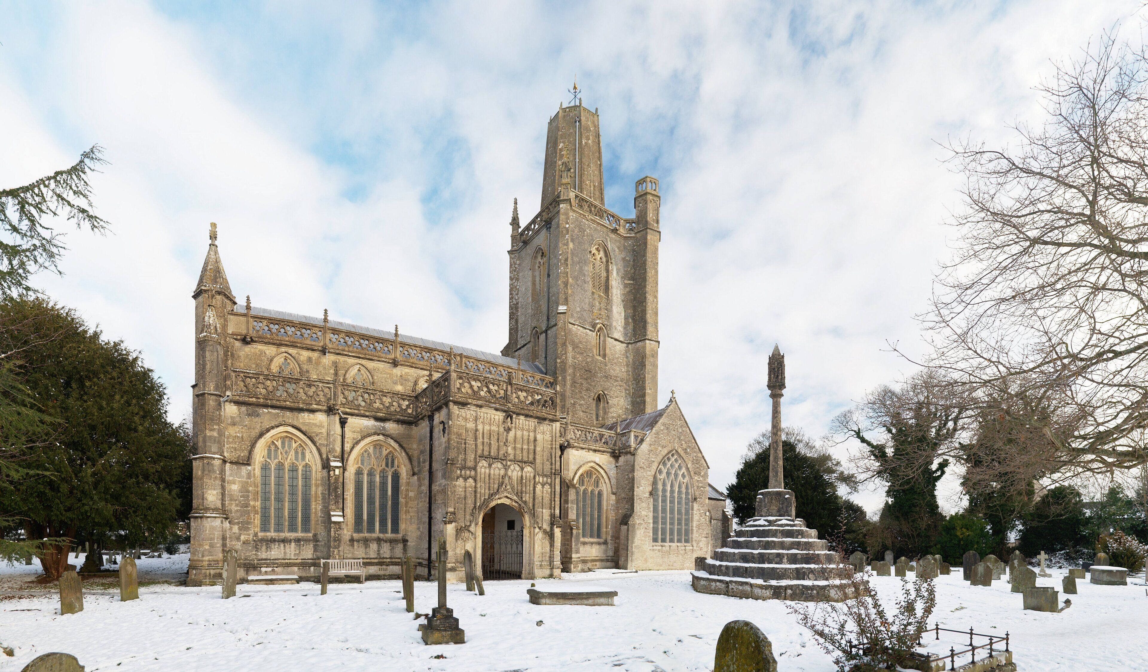 A Gothic church with a tall tower and a snow-covered graveyard.