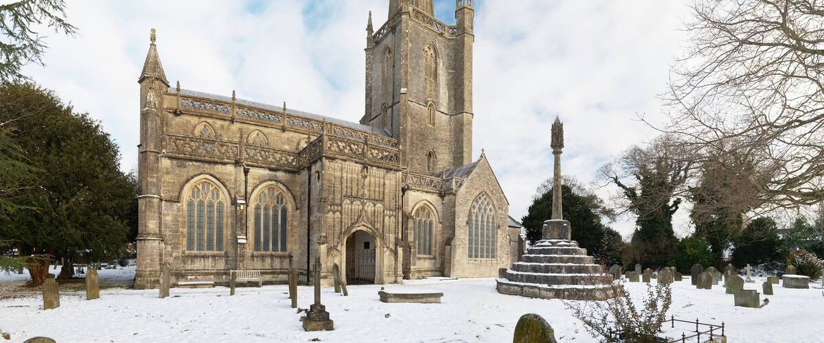 A Gothic church with a tall tower and a snow-covered graveyard.