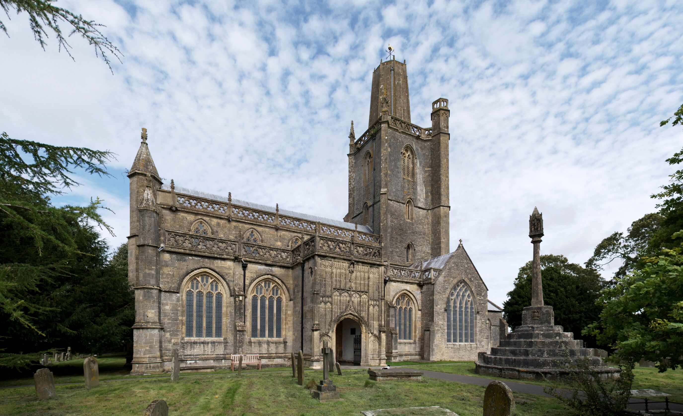 Wide view from the southwest of the parish church of [[w:Church of St Mary, Yatton |St Mary the Virgin, Yatton]], Somerset and (right) its churchyard cross