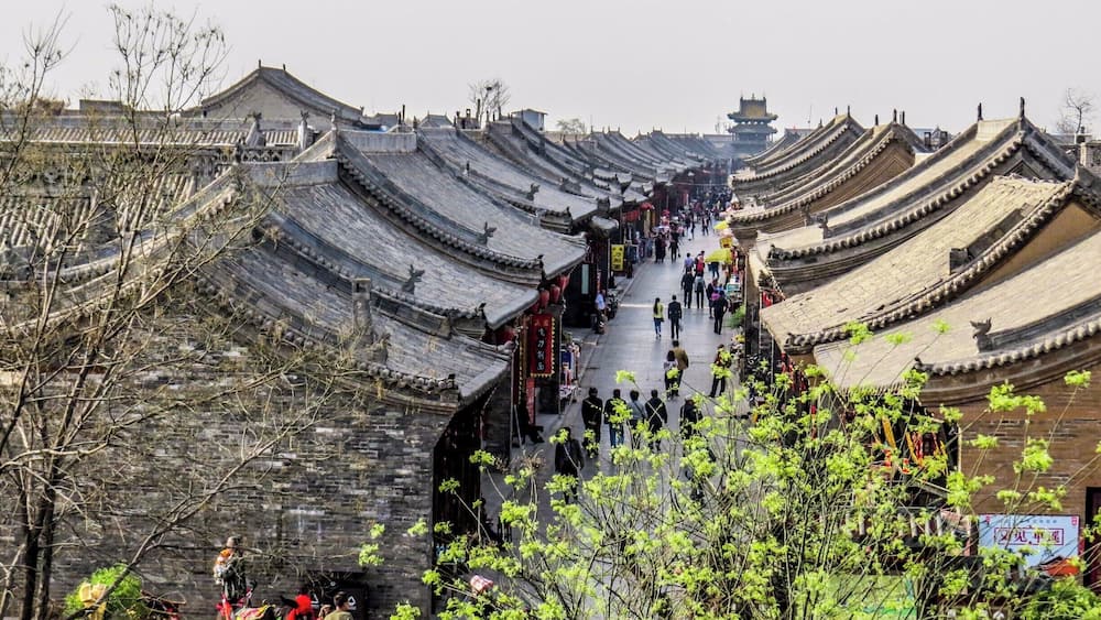A traditional Chinese street with tiered roofs and people walking.
