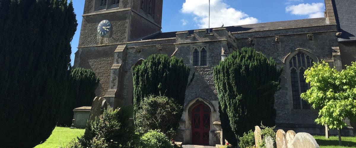 A church with a clock tower, a red door, and a flagpole.