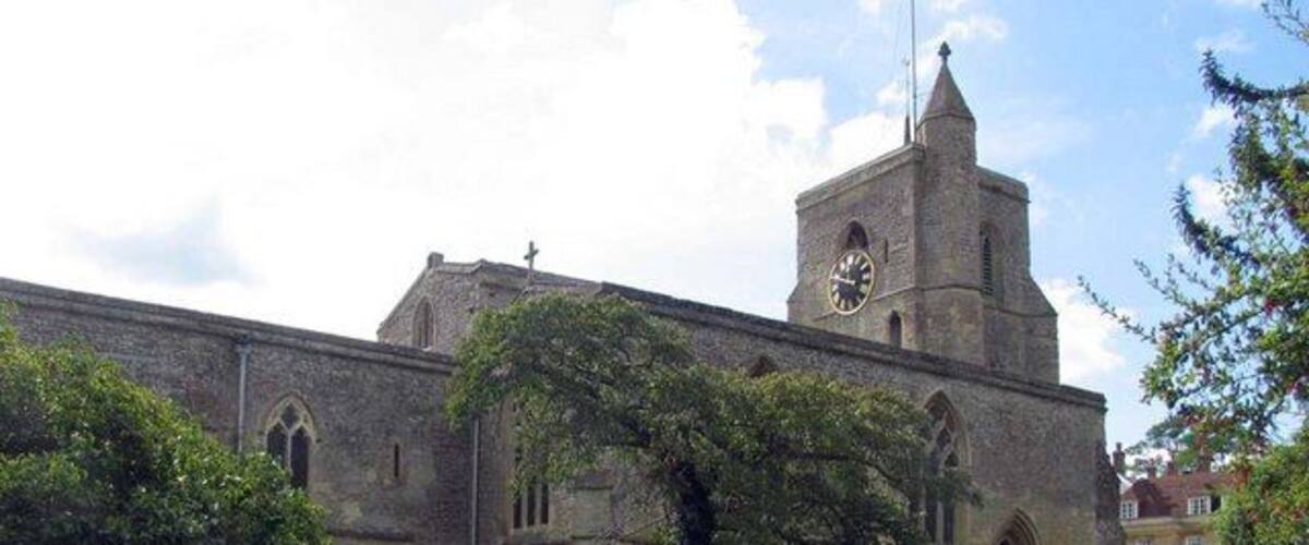 A church with a clock tower, surrounded by a cemetery with gravestones and a grassy path.