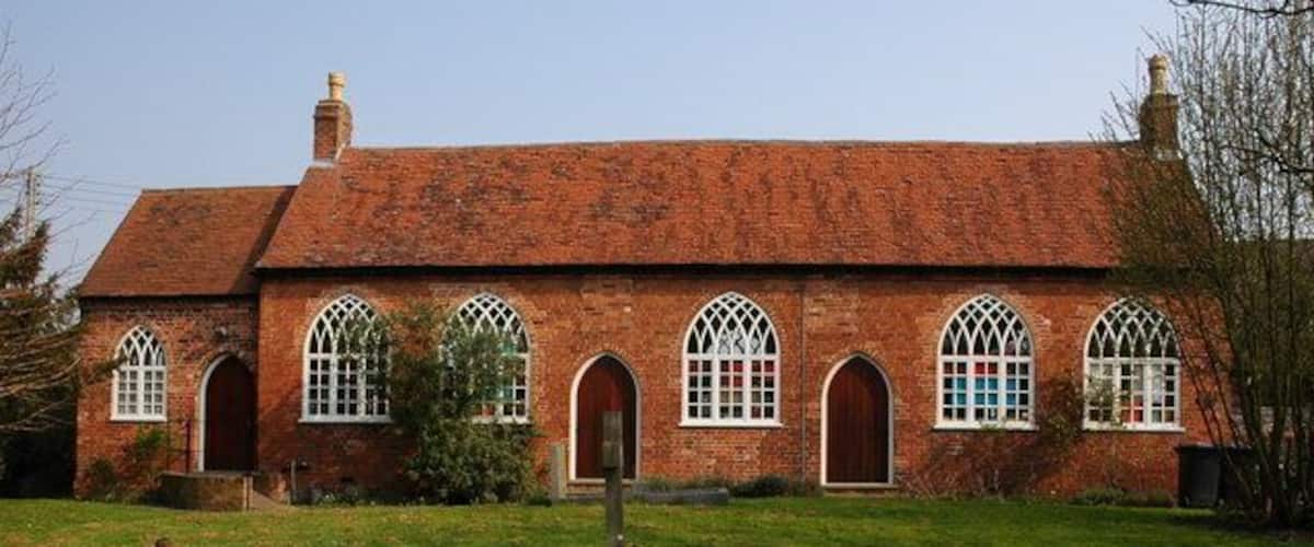 A brick building with arched windows and a grassy lawn.