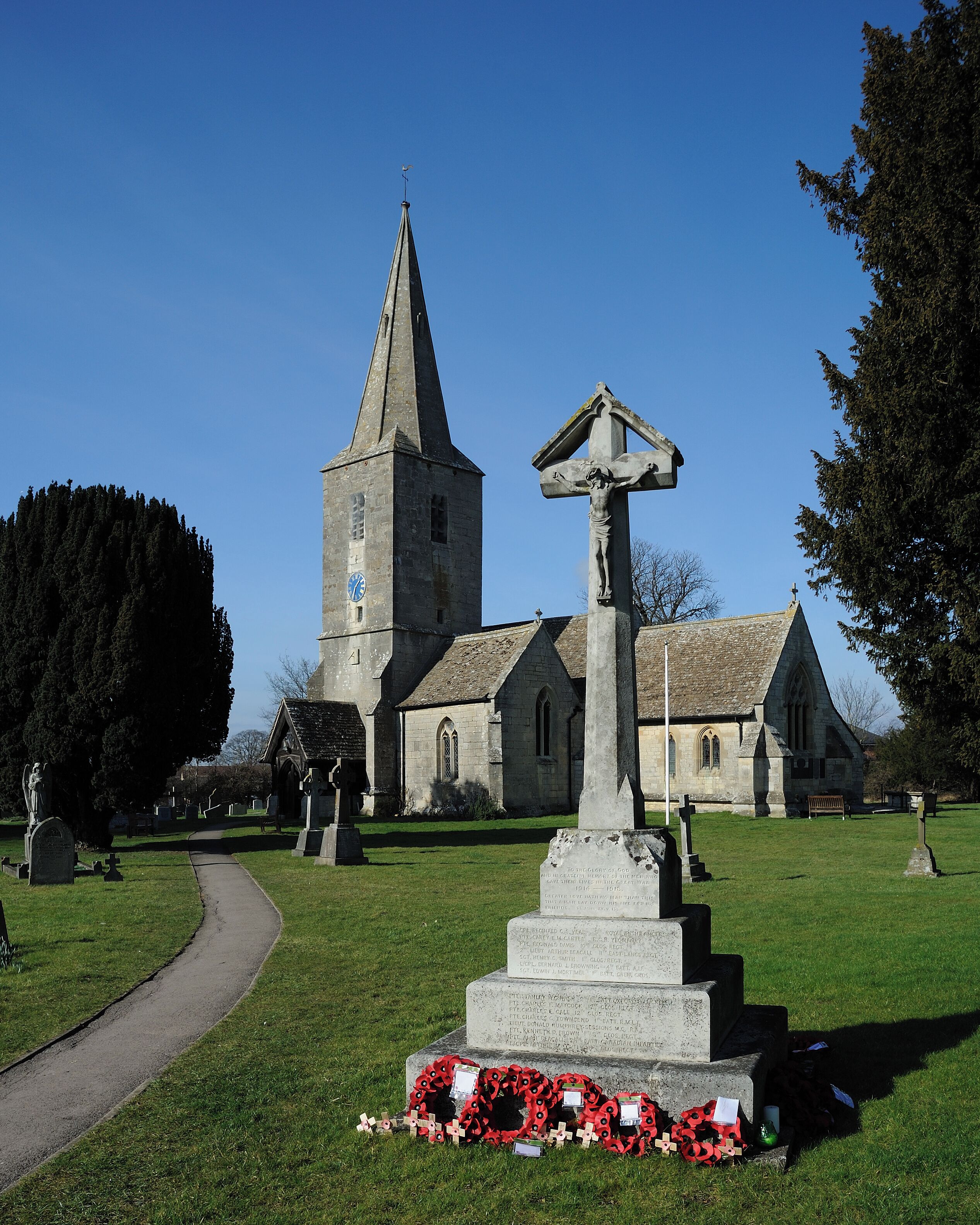 A church with a tall steeple and a cross monument in the foreground.