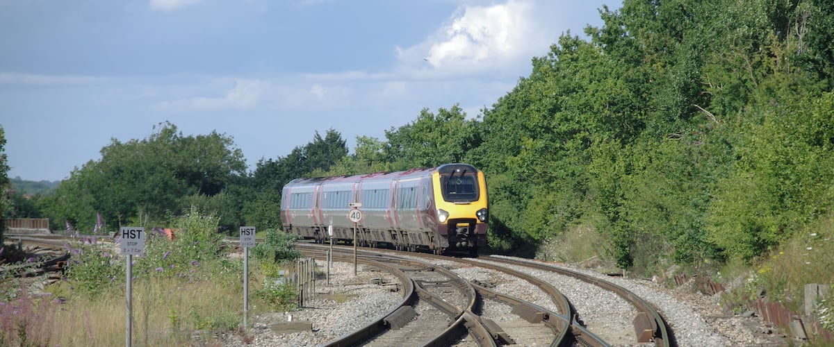 A train on railway tracks curving through a wooded area.
