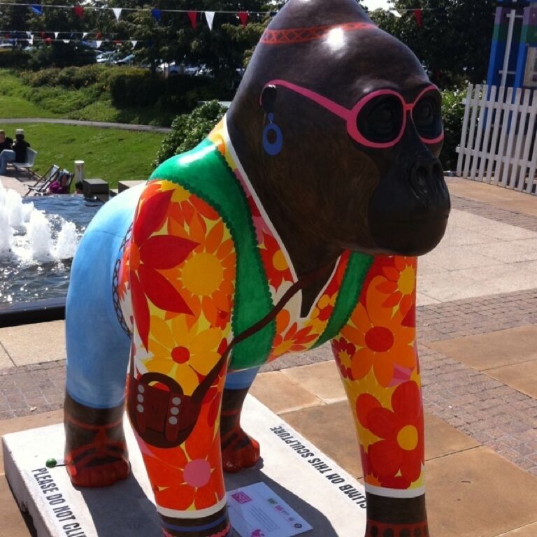 A colorful sculpture of a hippo wearing a floral outfit and glasses.
