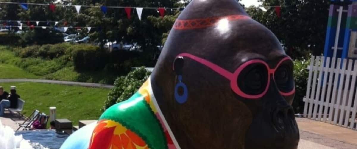 A colorful sculpture of a hippo wearing a floral outfit and glasses.